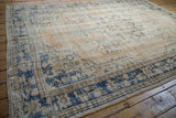 Patinaed Oushak carpet border, worn dusty navy patterns on beige ground, with visible selvage.