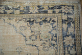 Distressed vintage Oushak rug corner, showing worn pile, dusty navy blue and sand motifs.
