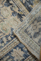 Distressed Oushak rug's textured pile, featuring worn patterns in dusty navy and beige.