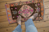 Vintage distressed Turkish Kars rug with coffee brown field and geometric, floral pinwheel patterns.