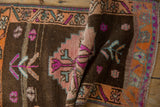 Textured pile of vintage distressed Kars rug showing coffee brown and vibrant geometric patterns.
