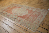 Vintage distressed Oushak rug corner, showing cinnabar spandrel and vine leaf border.