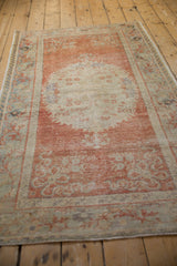 Distressed Oushak rug close-up: pale cinnabar red and blue vine border with even wear.