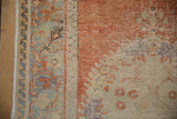 Distressed Turkish Oushak rug detail: worn pile revealing foundation, cinnabar, blue, beige vine border.