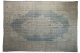 Distressed vintage Oushak rug, faded denim blue field, pale apricot medallion.