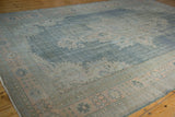 Distressed vintage Oushak carpet texture: worn denim blue field with pale apricot floral motifs.