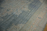 Distressed Oushak carpet, showing worn denim blue field and pale apricot border motifs.