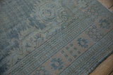 Worn denim blue and pale apricot tones on the distressed border of a vintage Oushak rug.