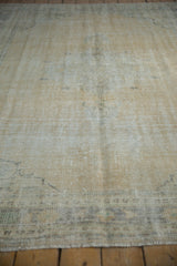 Faded ivory and sand distressed Oushak rug with worn pile and visible foundation.