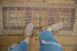 Detail of distressed vintage Oushak rug, triple medallions in lavender, beige, and turquoise with soft wear.