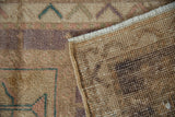 Close-up shows the distressed pile, visible foundation, and woven backing of the Oushak rug.