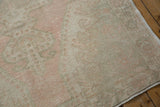 Distressed vintage Oushak rug showing muted blush, sea foam green patterns and low pile.