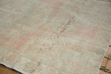 Close up of the vintage distressed Oushak rug showing soft blush, ivory, and beige tones with worn texture.