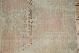 Distressed Oushak rug pile with blush, ivory, sea foam green tones and visible foundation.
