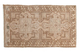 Distressed vintage Oushak rug with geometric double medallions, starburst border, beige, ivory tones.