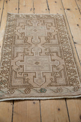 Lower corner of distressed Oushak rug, featuring geometric border and subtle silver tones.