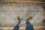 Worn pile of the distressed Oushak runner showing foundation, antique ivory, and chocolate brown border.
