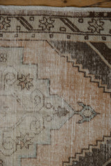 Distressed Oushak rug's worn pile and visible foundation, with geometric brown and beige patterns.