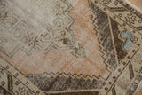 Distressed Oushak runner close-up: worn pile, visible foundation, dusty rose, brown, ivory tones.