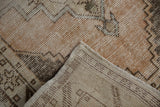 Distressed Oushak rug detail showing worn pile, visible foundation, and neat selvage.