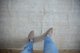 Distressed Oushak carpet surface, showing worn pile in ivory, beige, and seafoam.