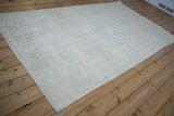 Textured edge of a distressed Oushak rug with ivory, beige, and seafoam green pile.
