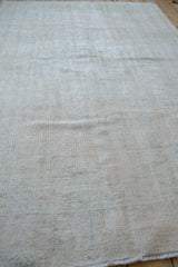 Decorative worn pile texture on this distressed Oushak carpet in ivory and cream.