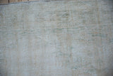 Distressed Oushak carpet's low pile, revealing soft ivory, beige, and seafoam green hues.