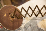 Back of vintage barber shaving mirror with rusty accordion extension and distressed brown surface.