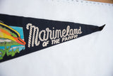 Angled view of the black felt Marineland pennant showing its cream rope-style lettering.