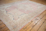 Corner of distressed pink and ivory Sparta rug with meandering floral arabesque border.