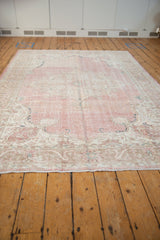 Distressed pink field and ivory main border with meandering floral arabesque pattern.