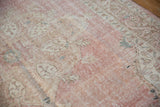 Distressed pink and ivory Sparta carpet pile, with soft blue floral arabesque and visible knot heads.