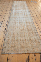 Distressed vintage Oushak runner, showing faded beige and brown floral gul motifs.