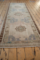 Vintage Distressed Oushak runner displaying faded geometric floral medallions and pinwheel border.