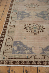 Distressed Oushak runner's coffee brown pinwheel border and faded geometric field.