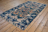 Geometric indigo and terracotta gul motifs with even wear on a vintage Oushak rug runner.
