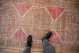 Distressed Oushak runner with abrashed ground, featuring geometric floral medallions in pink, beige, and sage.