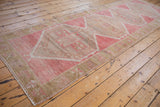Distressed Oushak runner section featuring geometric floral, shadow hook motifs in pink, beige, sage.