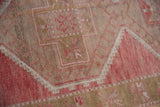 Distressed vintage Oushak runner, close-up geometric latch motif in soft raspberry red and beige abrash.
