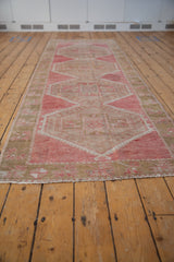 Distressed pile and nuanced floral border details of a pink and beige vintage Oushak rug.