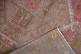 Distressed Oushak rug pile showing even wear to knot heads, pink and beige tones, and secured selvage.