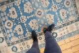 Distressed sky blue Oushak rug with oversized ivory floral palmettes and delicate vinery.