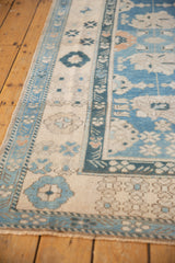 Distressed vintage Oushak rug corner showing blue palmette patterns and restored selvage.