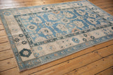 Distressed Oushak rug detail with sky blue field, ivory palmettes, and delicate peach blossoms.