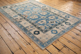 Faded sky blue floral palmette and delicate vinery on a distressed Oushak rug corner.