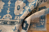 Rolled Vintage Distressed Oushak rug, highlighting sky blue floral palmettes, ivory tones, and even wear.