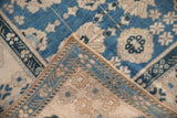 Reverse weave and intact selvage of a distressed Oushak rug corner.