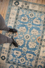 Distressed Oushak rug section showing sky blue field, ivory palmettes, and intricate navy border.