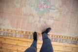 View from above showing the soft, worn texture of a distressed Kars carpet in blush, mint green, and pale bronze.